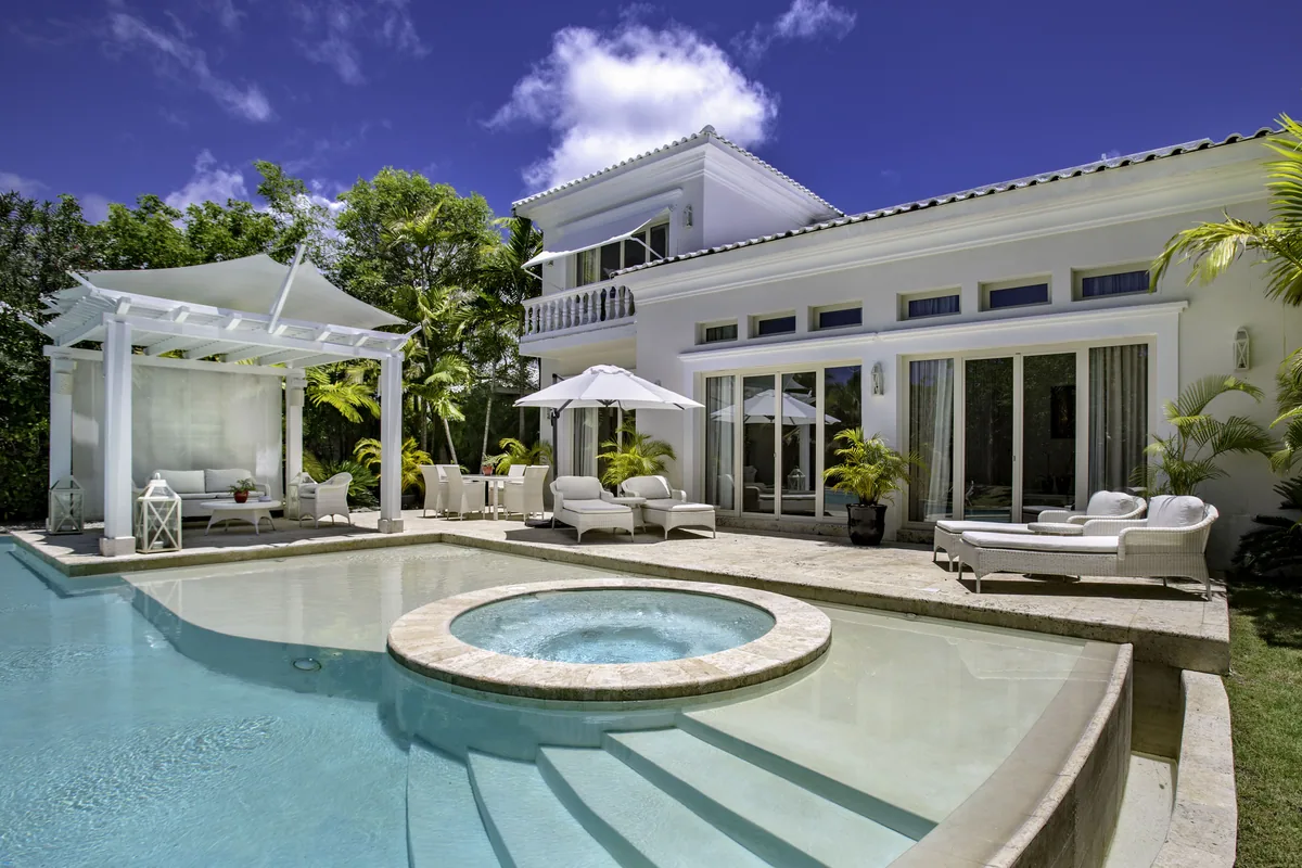 A white villa with a lit pavilion over its pool